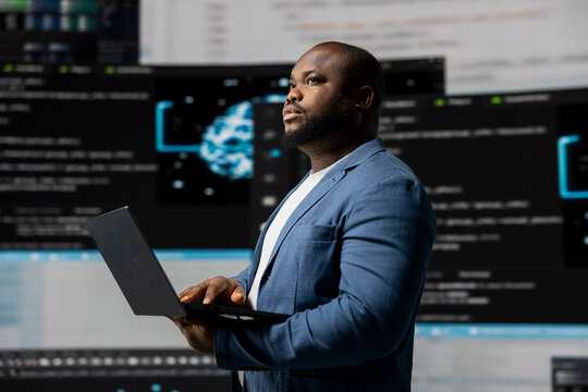 African american coder expert immersing in software development for a high tech work environment, focused on laptop screen. Engineer enjoying coding life and IT cloud computing.