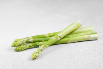 Bunch of raw fresh green asparagus stalks on light gray textured background. Healthy food, fresh...