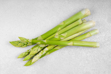 Bunch of raw fresh green asparagus stalks on light gray textured background. Healthy food, fresh...