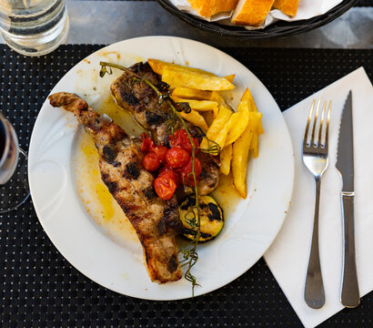 Lunch is served for guests in grill house restaurant. Grilled Churasko ribs, French fries and baked vegetables..