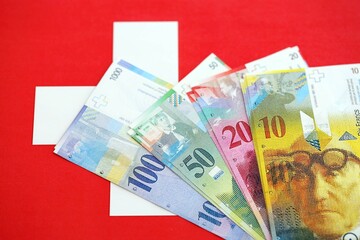Swiss franc banknotes and flag. The current francs money bills lies on flag in big amount