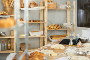 Professional light bakery kitchen with work table, bread bun baking in deck, stuff, dough, cabinet and ingredient for baking. Close up