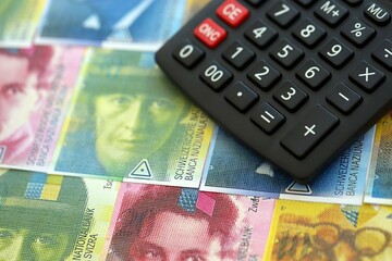 Swiss franc banknotes and calculator. The francs money bills and calc lies on table