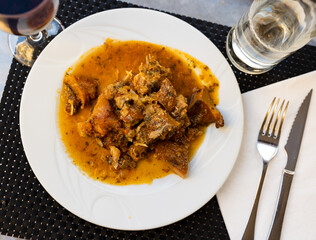 Rabbit meat cooked with saffron milk caps, carrots and Provencal herbs. Dish is complemented by glass of red wine..