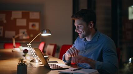 Enthusiastic man working night office closeup. Smiling businessman browsing