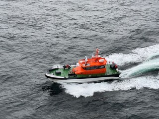 orange pilot boat alongside ship