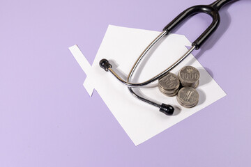 Home, Health & Wealth Concept – Paper House with Stethoscope and Coins on Desk