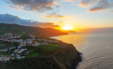 Aerial view of a colorful sunset over the dramatic coastline of São Miguel Island in the Azores, Portugal, with green fields and Atlantic Ocean