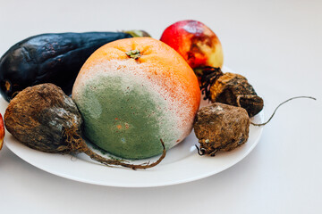 Rotten fruits and vegetables on a plate showcasing food decay and waste