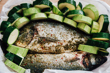 Freshly prepared fish and zucchini ready for baking in a cozy kitchen setting