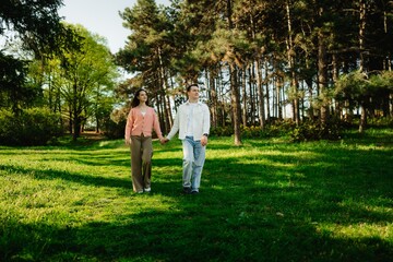 Couple strolls hand in hand through a serene forest on a sunny day