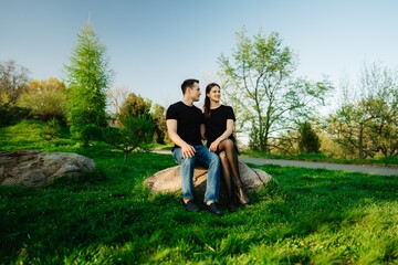 Romantic couple sharing a quiet moment on a rock in a lush green park
