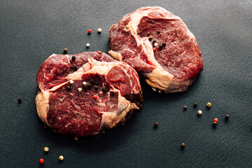 Freshly cut beef steaks with spices arranged on a dark surface ready for cooking