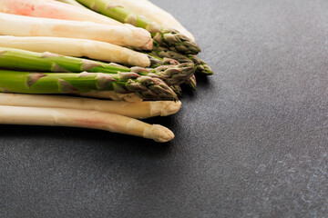 Fresh green and white asparagus arranged on a dark surface ready for cooking or serving