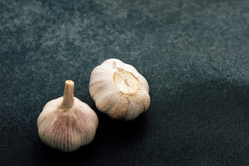 Garlic bulbs resting on a dark surface highlighting their texture and unique shape