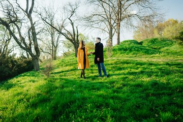 Couple enjoying a romantic walk in a lush green park during golden hour