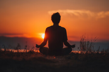 Silhouette meditating at sunset on grass field. Serene and peaceful zen moment. Mindfulness, spiritual awakening, inner peace.