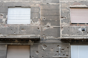 The faзade of an old building, mottled with numerous bullet and shrapnel marks, testifying to the...