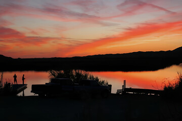 A panoramic view of two fishermen standing on a dock taken at sunset on Mittry Lake just North of Yuma, Arizona
