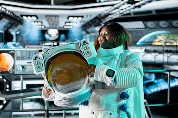 Astronaut holds helmet inside space station, preparing for mission outside, on hostile planetary habitat. Starship crew member beginning landing procedures on extraterrestrial planet