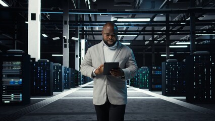 IT professional looking over data center checkup checklist paperwork on tablet. African american...