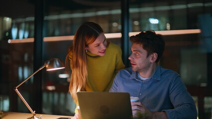 Smiling colleagues discussing startup looking laptop late evening closeup. 