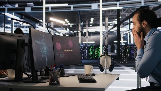 Employee requesting help from manager to fix hacked equipment systems. Stressed data center admin reacting to spyware popup on computer screen, launching emergency response protocol, camera A