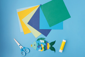 Kids marine paper craft with colorful fish and tools on blue background for DIY kits, art supply...