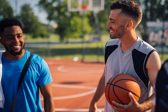 Basketball player smiling with friends on outdoor court