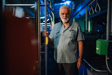 Senior man entering public transport bus at night