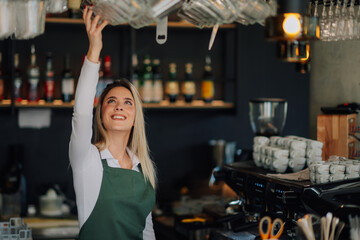 Smiling barista reaching for glass in cafe