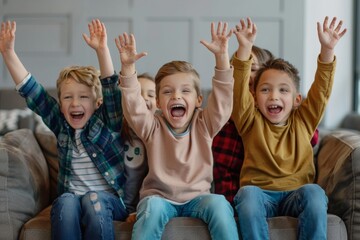 Excited children sitting on sofa in living room and raising hands up