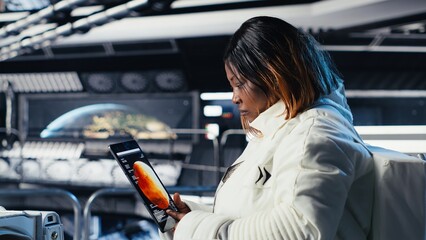 Astronaut using tablet to check analytics after completing red planet surface mission on unfamiliar...