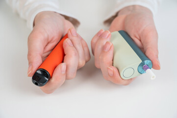 Woman holding electronic cigarette and disposable vape on white background. Tobacco heating systems...