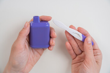 Woman holding pregnancy test and e-cigarette. 