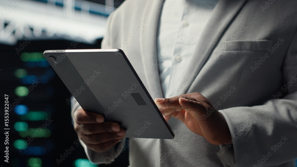 Poster close up of system administrator walking in data center, using tablet to check gear for system stabi