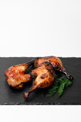 Roasted chicken leg quarters with crispy skin served on a black stone tray with a bunch of fresh...