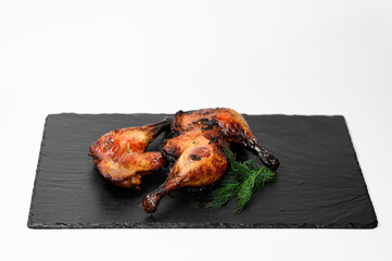 Roasted chicken leg quarters with crispy skin served on a black stone tray with a bunch of fresh...