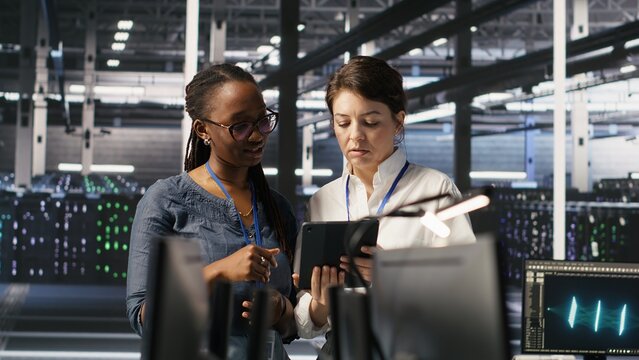 Data center teamworking colleagues performing maintenance on server racks used for artificial intelligence processing. Engineering team managing server hub rigs used for machine learning, camera A - Powered by Adobe