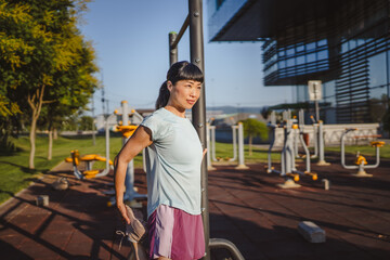 Japanese woman in a sportswear stretching in park before workout