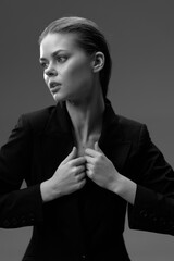 Black and white portrait of a young woman in a dark blazer looking thoughtfully to the side with...