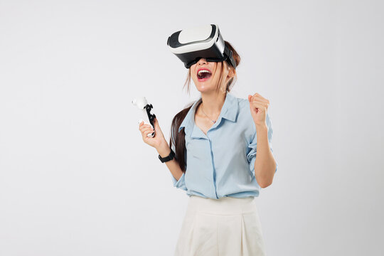 Game success for Excited young Asian woman using joystick controller in VR headset game, thrilled by the innovation of digital reality experience. isolated studio white background