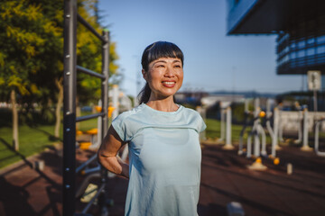 Japanese woman in a sportswear stretching in park before workout