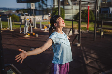 Japanese woman in a sportswear stretching in park before workout
