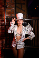 Performer in a sparkling costume and white top hat posing for the camera. Bright stage look in...