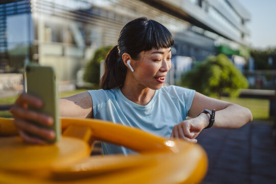 mature japanese sportswoman check her performance data on smart watch