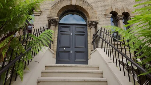 Approaching a black front door to a townhouse or home with stairs and metal railings.