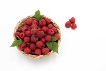 Woven Basket Filled with Ripe Red Raspberries and Green Leaves Isolated on White