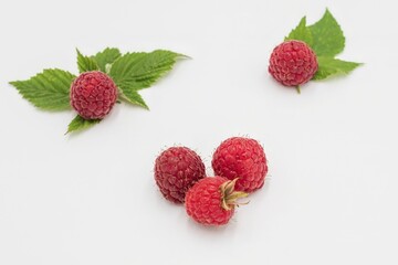 Ripe red raspberries with leaves on white background, macro close-up composition