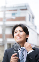 Hard working businessman sweating in hot weather Image of a handy fan cooling him off Be careful of...
